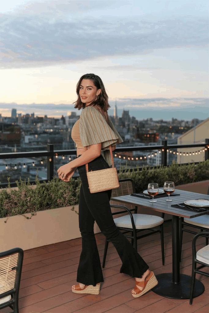 woman mid-step in black flare leggings, a flutter-sleeve cotton blouse, tan espadrille sandals, and a straw crossbody bag
