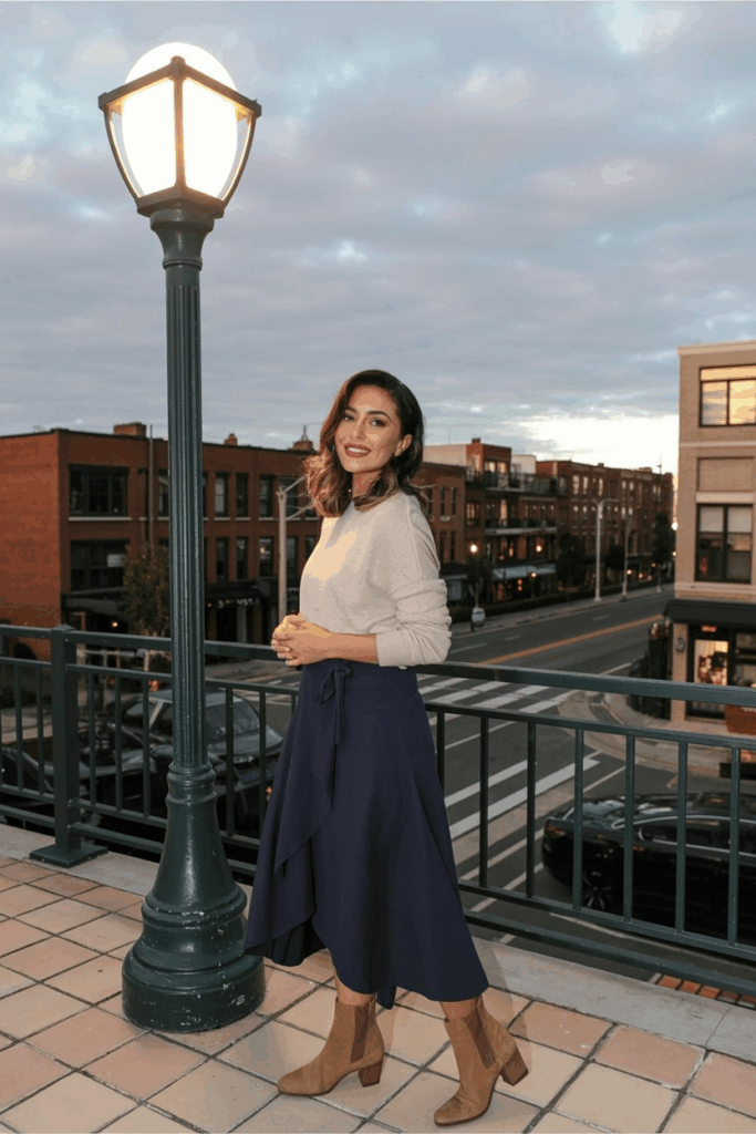 woman wearing a navy wrap skirt and tan suede ankle boots, paired with a tucked sweater.