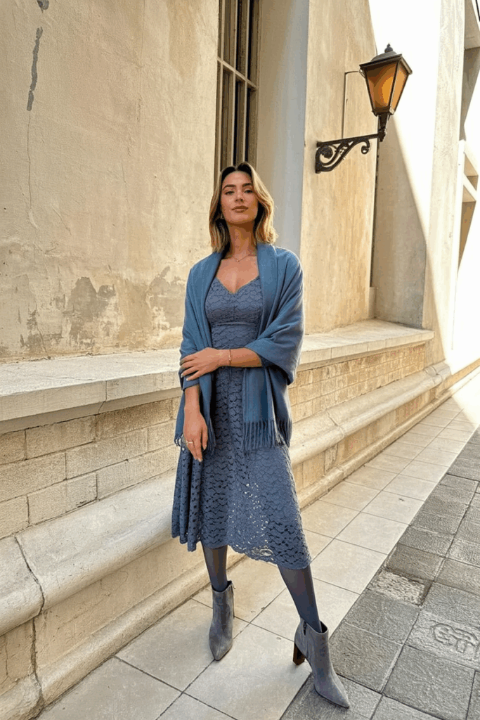 woman wearing a slate blue lace midi dress with long sleeves, thick thermal tights, a matching wool shawl, and gray suede heeled boots