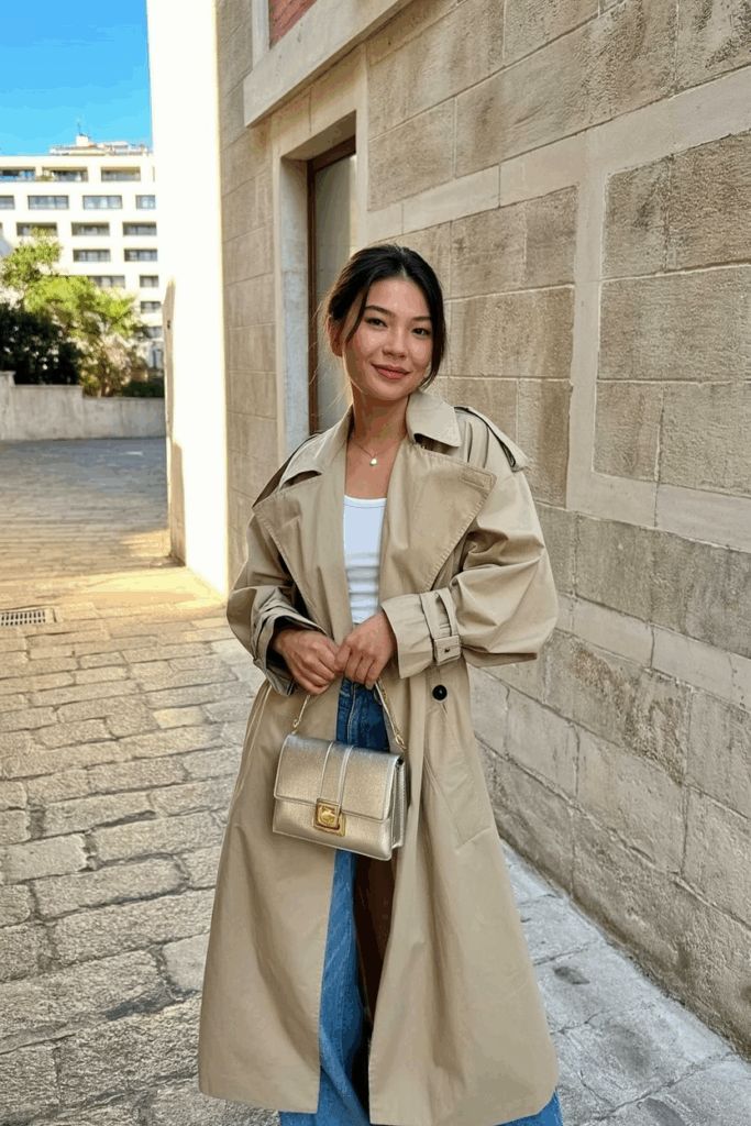 Asian Woman wearing an oversized beige trench coat, carrying a structured mini bag