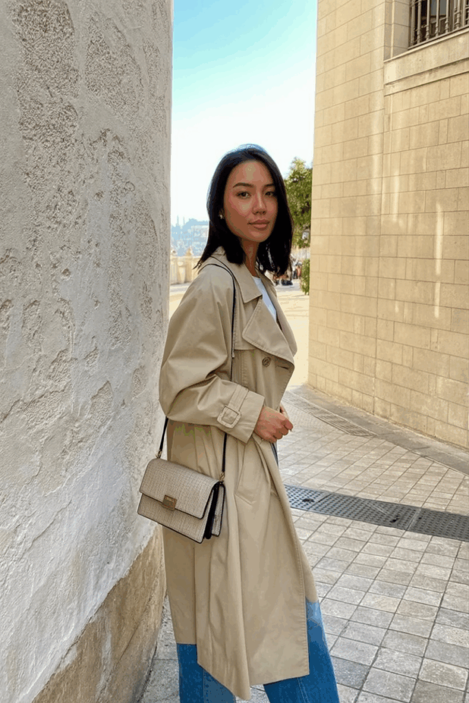Asian Woman wearing an oversized beige trench coat, carrying a structured mini bag