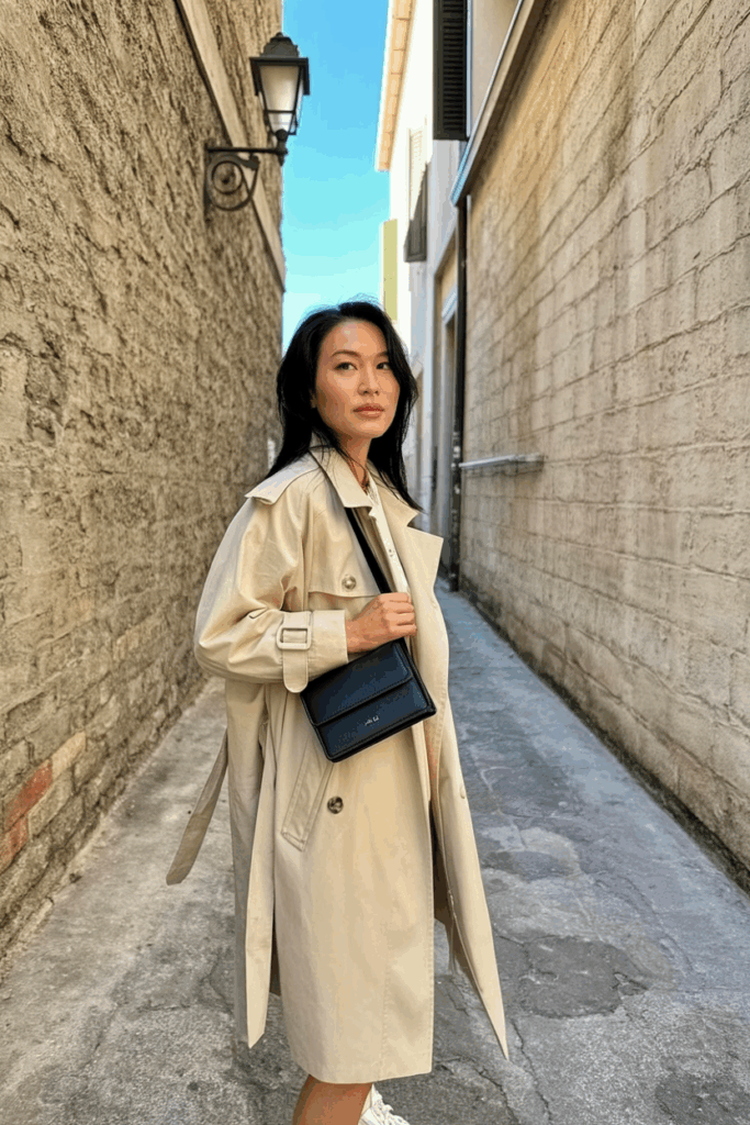 Asian Woman wearing an oversized beige trench coat, carrying a structured mini bag