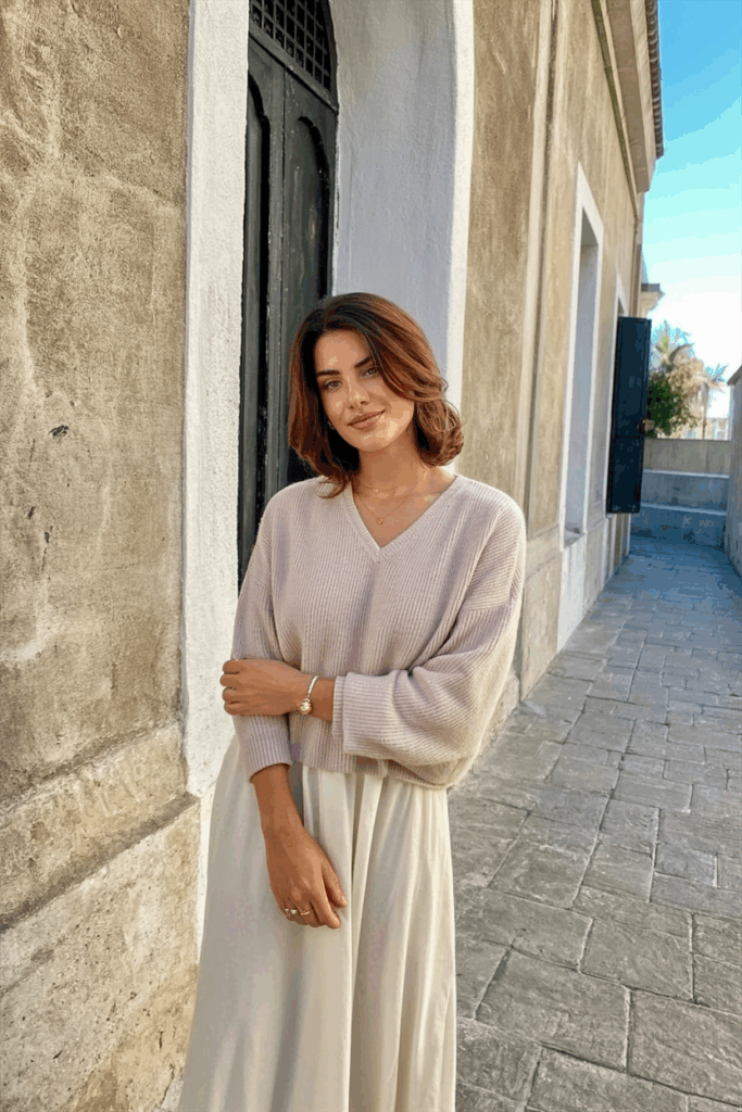 woman wearing a soft pastel cashmere sweater over her shoulders, styled over a midi dress