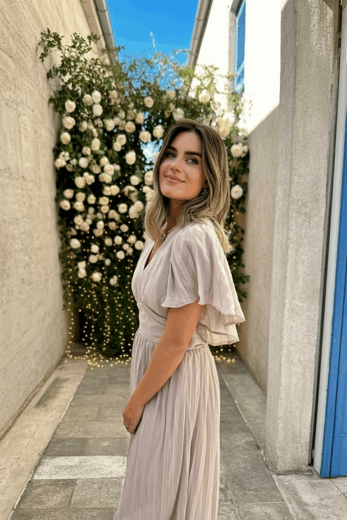 Woman wearing a blush-toned chiffon dress with flutter sleeves