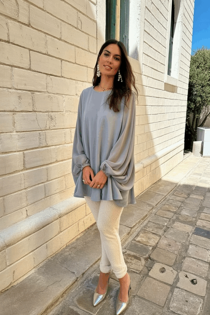 A woman wearing a dove-gray georgette gown with long chiffon sleeves, warm fleece-lined leggings, paired with pearl drop earrings and silver pointed-toe heels