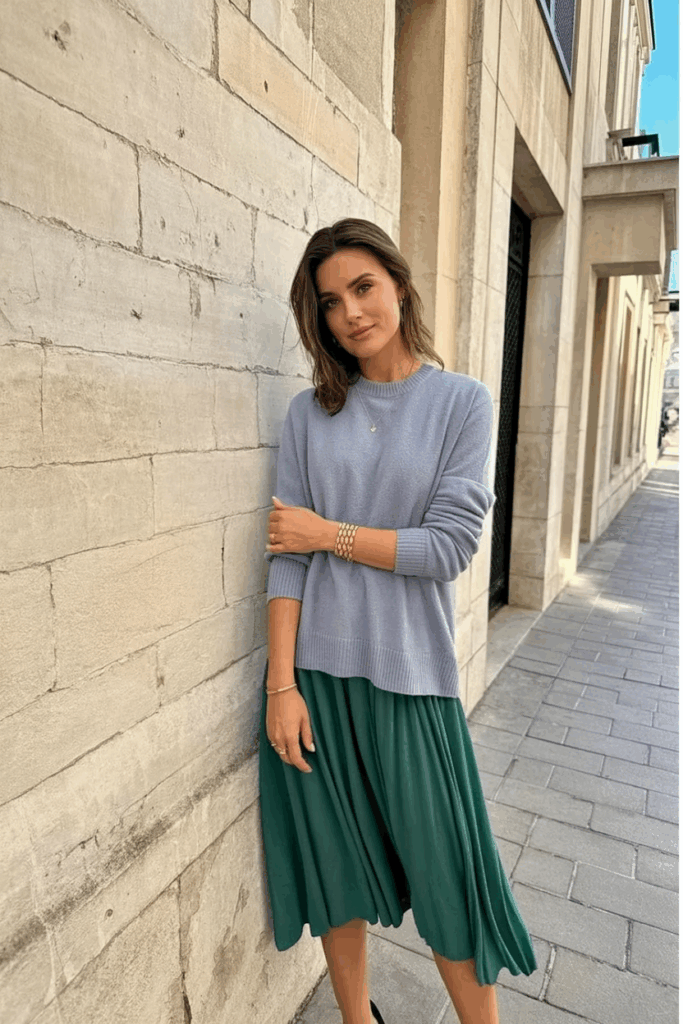 woman wearing a soft pastel cashmere sweater over her shoulders, styled over a midi dress