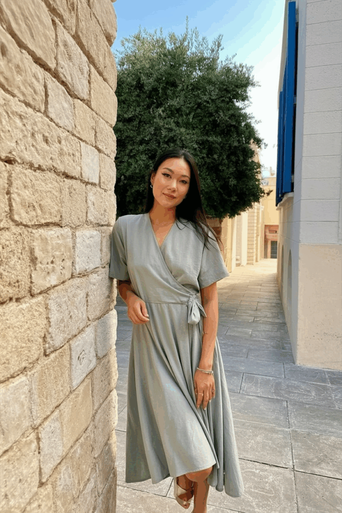 wearing a soft A-line wrap dress in muted green