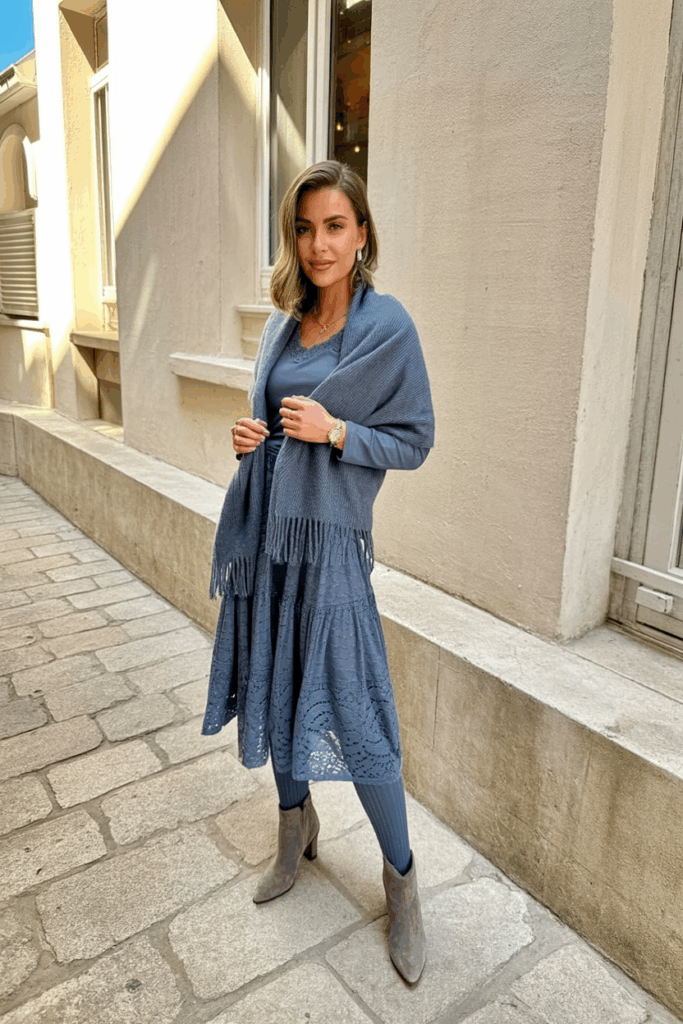 woman wearing a slate blue lace midi dress with long sleeves, thick thermal tights, a matching wool shawl, and gray suede heeled boots