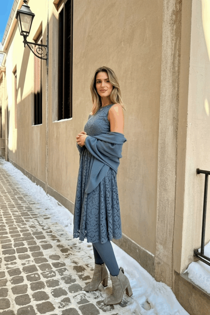 woman wearing a slate blue lace midi dress with long sleeves, thick thermal tights, a matching wool shawl, and gray suede heeled boots