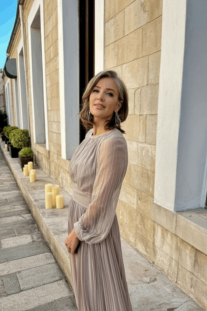 A woman in her 50s wearing wearing an elegant chiffon dress with Sheer long sleeve in muted rose