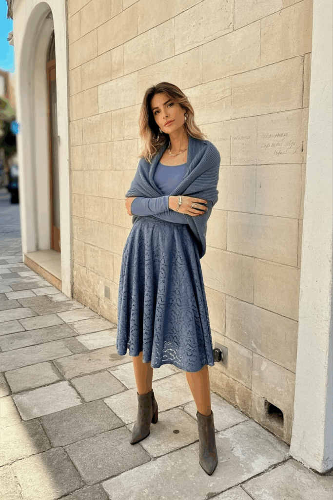 woman wearing a slate blue lace midi dress with long sleeves, thick thermal tights, a matching wool shawl, and gray suede heeled boots