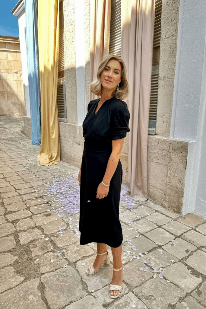 A woman in her 50s wearing a black midi dress