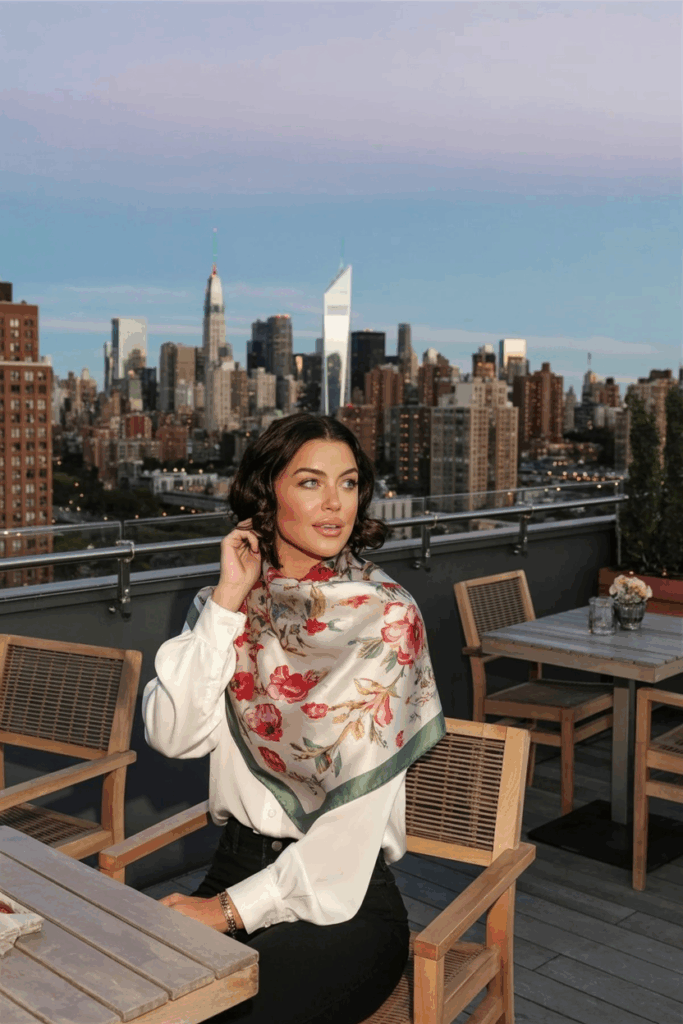 woman wearing a floral silk scarf around her neck, a white blouse and black pants