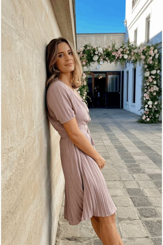 Woman in a dusty rose Tea-Length dress with short sleeves.