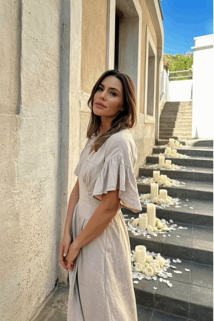 Woman wearing a blush-toned linen dress with flutter sleeves.