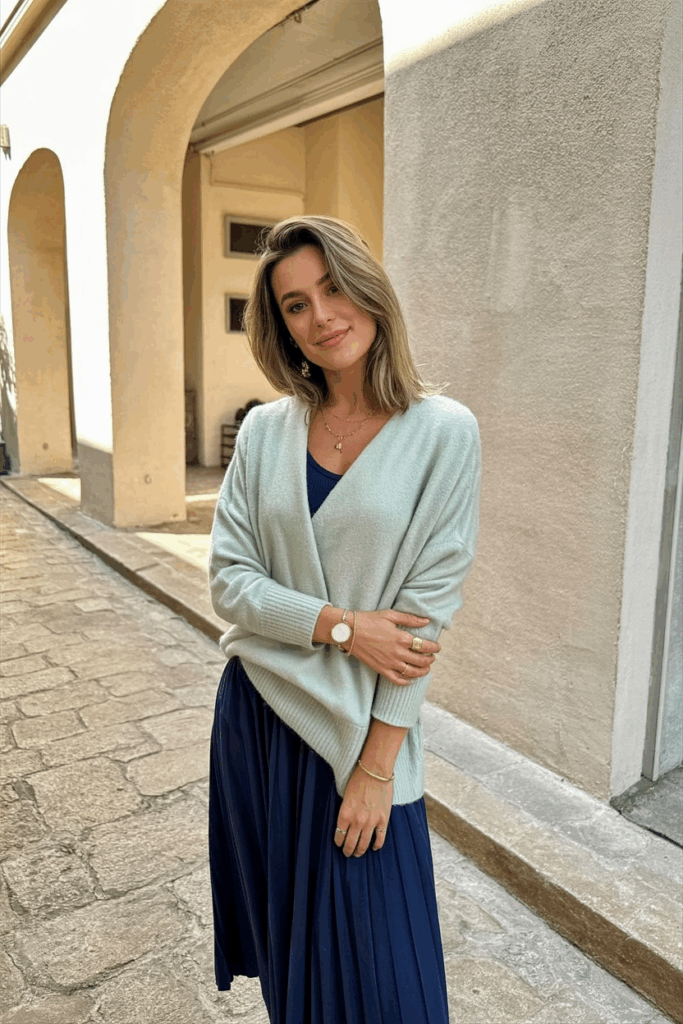 woman wearing a soft pastel cashmere sweater over her shoulders, styled over a midi dres