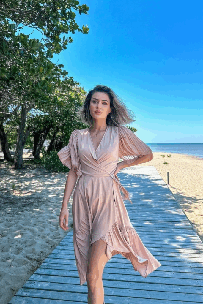 light coral wrap dress with flutter sleeves and a midi-length hem, cinched at the waist