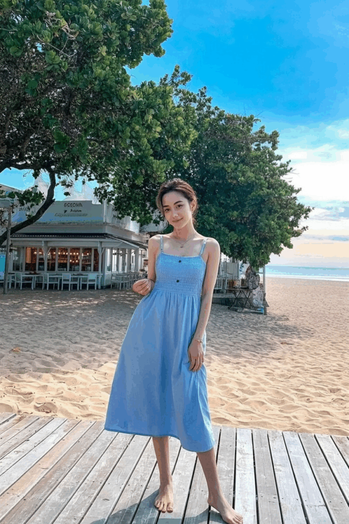 A woman in a soft pastel blue cotton sundress with thin straps and a skirt