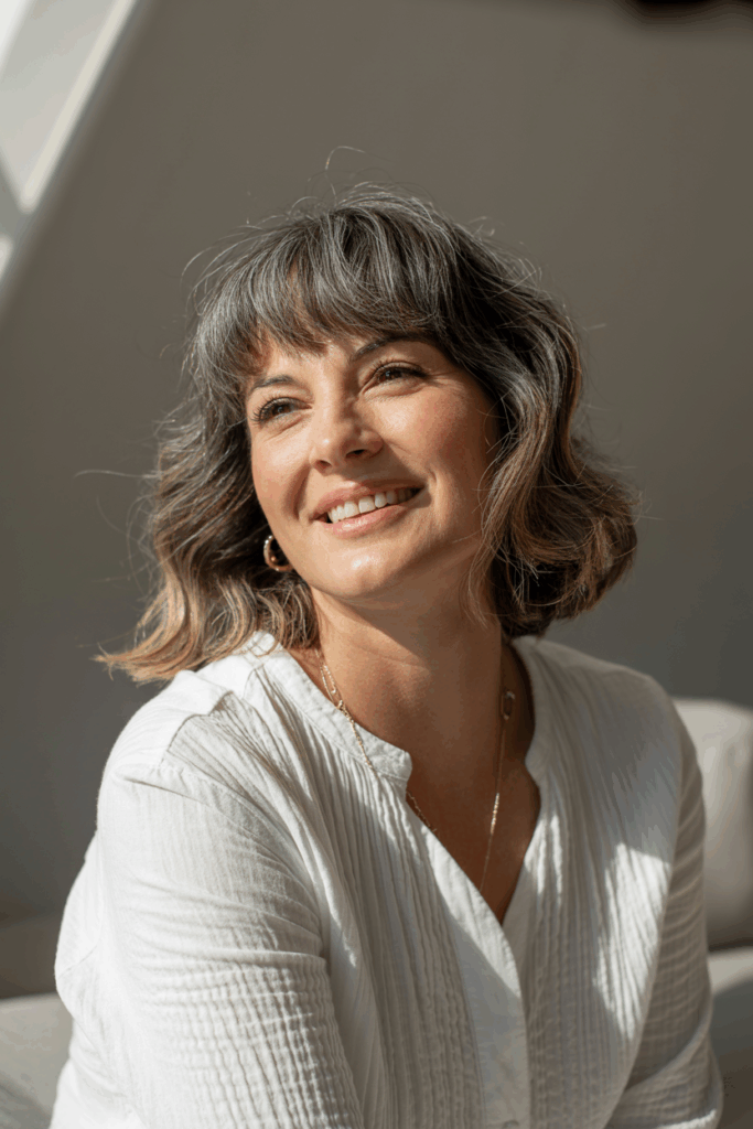 A woman with curtain bangs framing her face, medium waves,