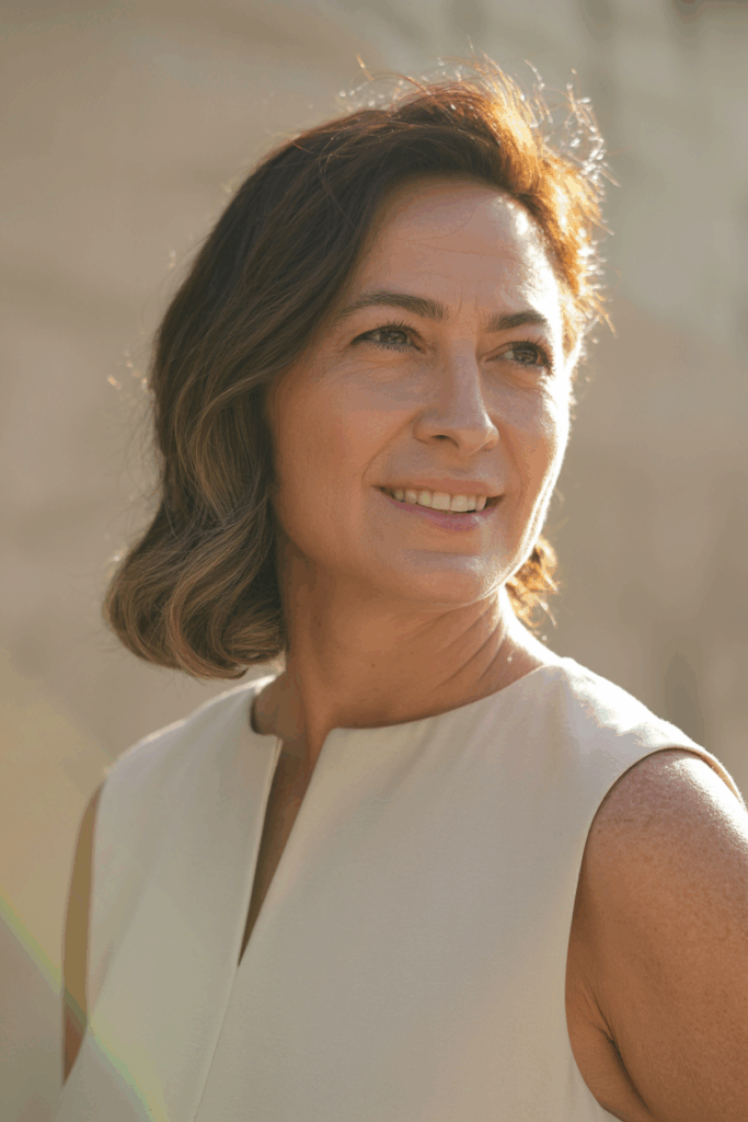 A woman with medium-length hair parted to the side, gentle volume at the roots