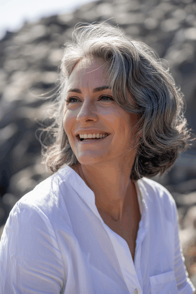 A woman with medium-length natural gray hair, soft waves
