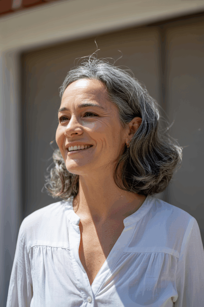A woman with medium-length natural gray hair, soft waves
