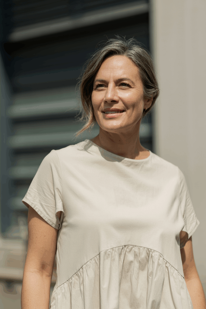 A woman with medium-length hair parted to the side, gentle volume at the roots