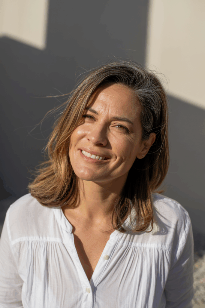A woman with shoulder-length hair and soft caramel highlights