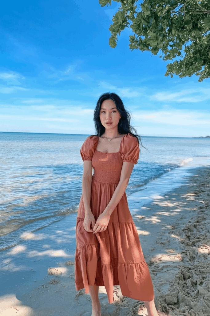 woman in a coral sundress with puff sleeves and a tiered skirt at calf length