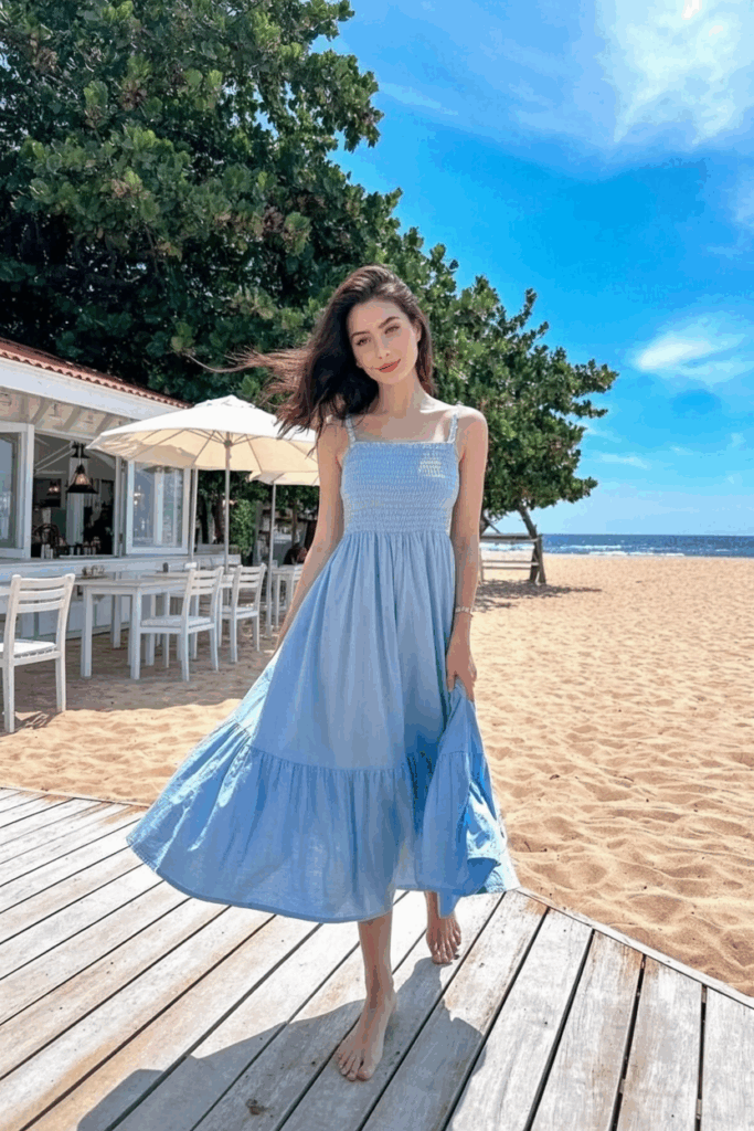 A woman in a soft pastel blue cotton sundress with thin straps and a skirt