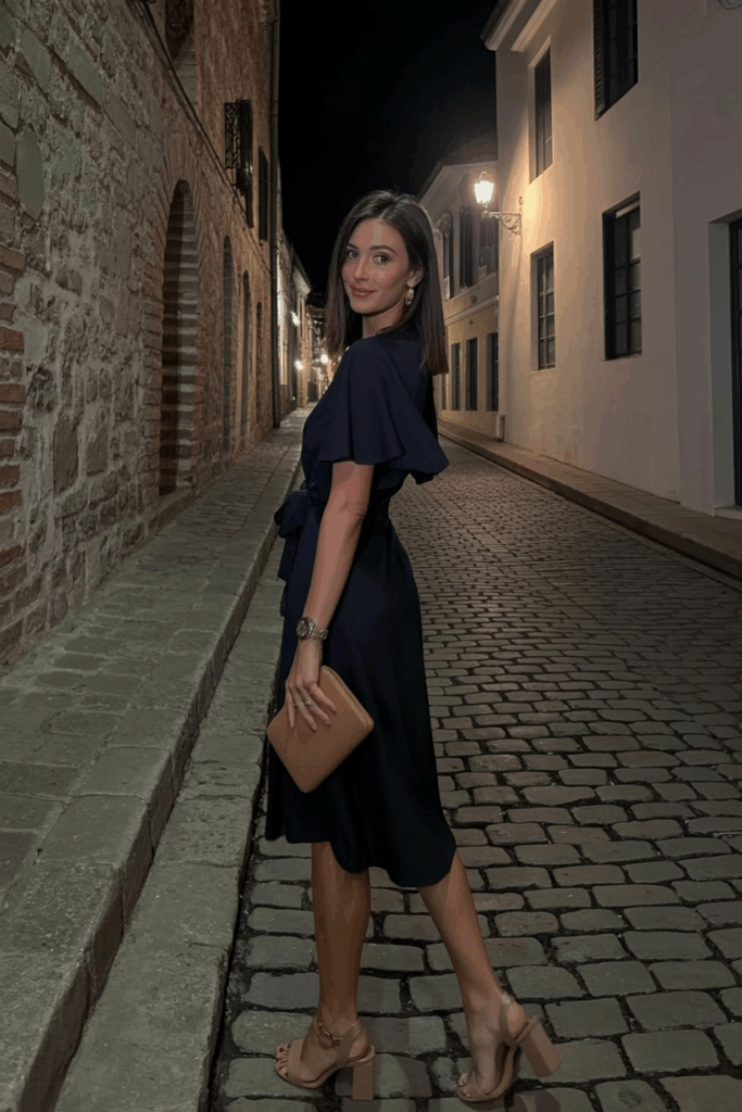 navy wrap dress with flutter sleeves and a tie waist, paired with block heels and a small leather clutch