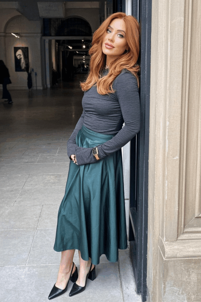 A woman wearing a fitted jersey long-sleeve top and flowy midi skirt with slingbacks