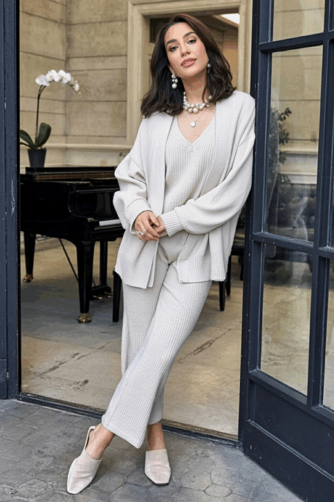 A woman wearing a soft knit co-ord set with pearl accessories and flat mules