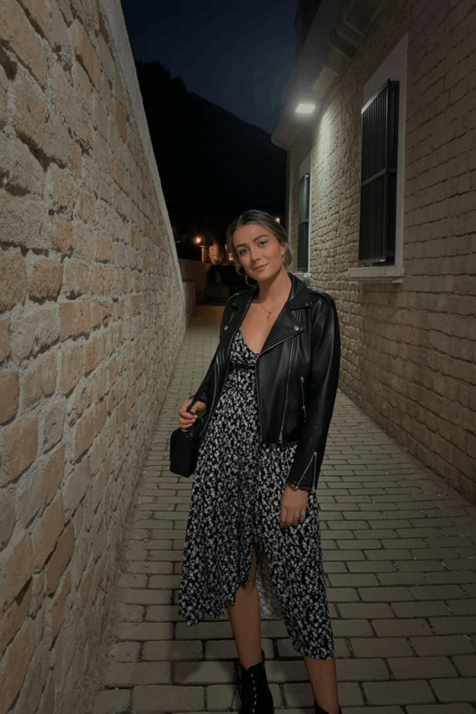 black leather jacket over a flowy floral midi dress, lace-up boots, and a crossbody bag