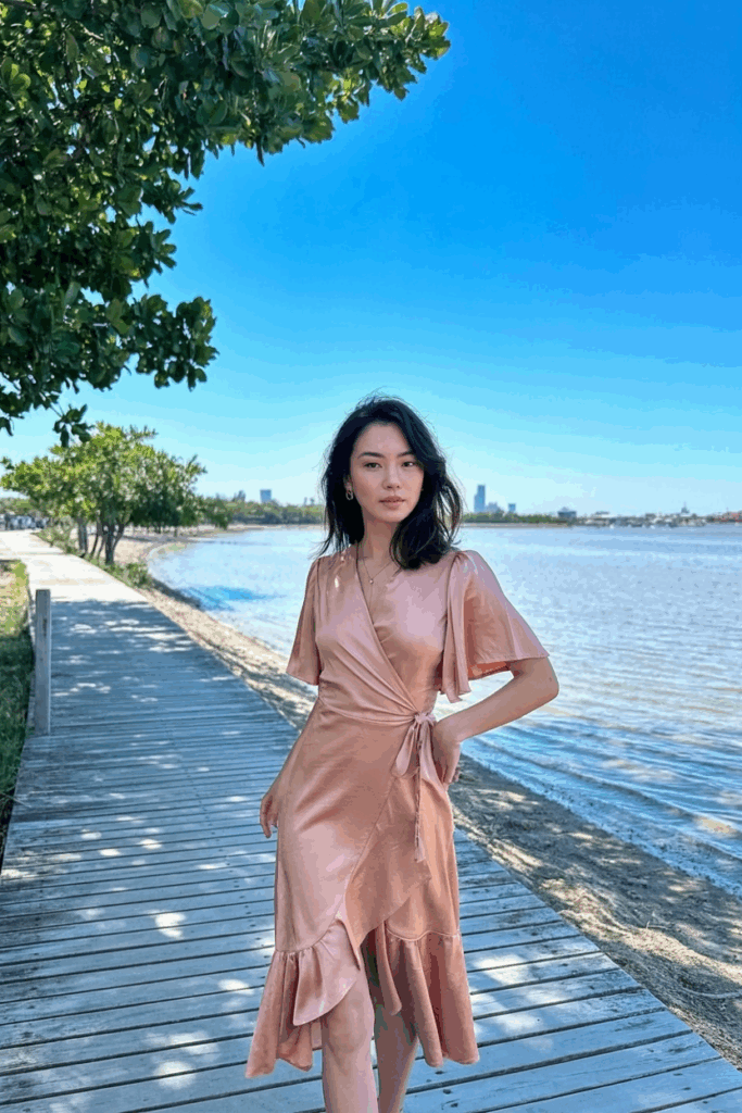 light coral wrap dress with flutter sleeves and a midi-length hem, cinched at the waist