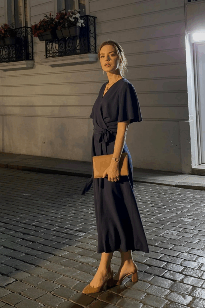 navy wrap dress with flutter sleeves and a tie waist, paired with block heels and a small leather clutch