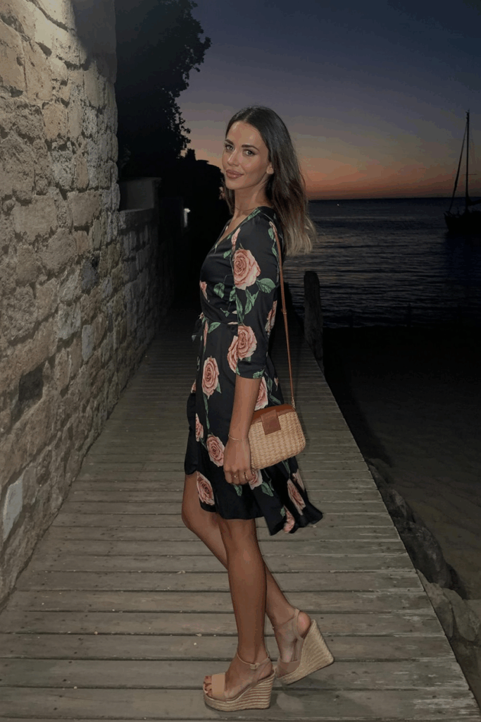 rose-print wrap dress with three-quarter sleeves, nude wedge heels, and a woven crossbody bag