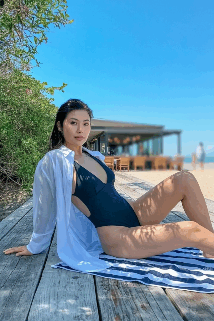 Sleek black one-piece swimsuit under a long, unbuttoned sheer white shirt