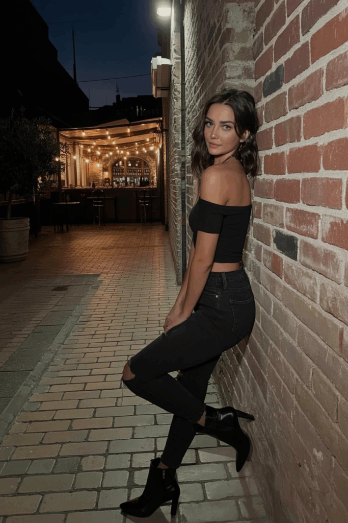 woman wearing high-rise black jeans with an off-shoulder fitted top and pointed ankle boots,